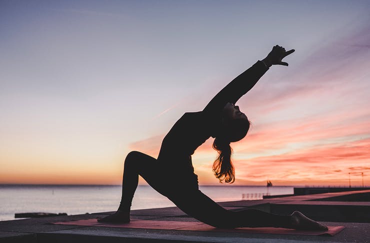 Photo of a lady practicing yoga at dawn